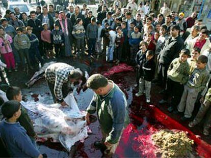 Niños palestinos observan cómo varios carniceros despiezan una res durante la fiesta del cordero.