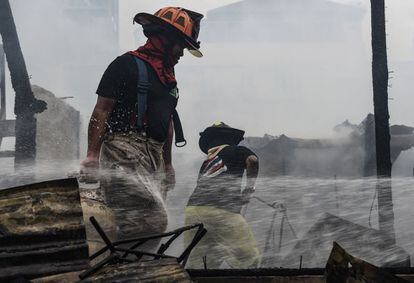 Los bomberos tailandeses trabajan para apagar las brasas después de un incendio residencial en el distrito de Phaya Thai, en Bangkok (Tailandia).