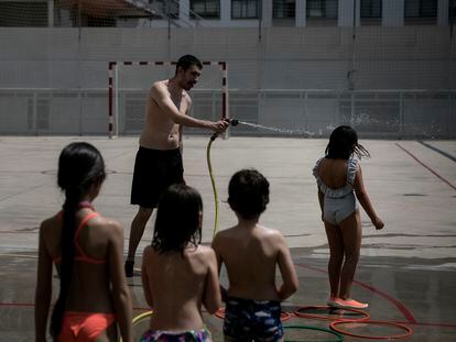 Un profesor refresca a alumnos en una escuela de Barcelona, el pasado mes de junio durante la ola de calor.
