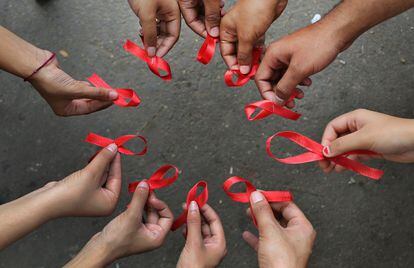 Un grupo de activistas de una ONG posan sosteniendo un lazo rojo en sus manos, el s&iacute;mbolo de la Lucha Contra el Sida. 