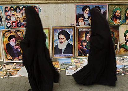 Dos iraquíes pasan por delante de un puesto de retratos del líder chií Alí Sistani en un barrio de Bagdad.
