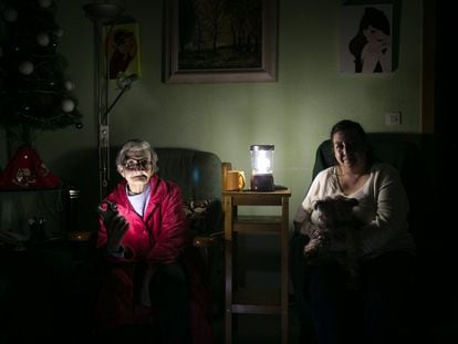 Dos mujeres iluminan con linternas el salón de su casa, en Barcelona en 2020.