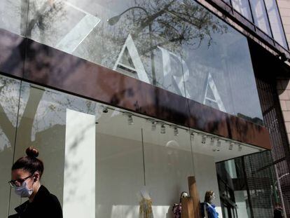 Una mujer con mascarilla pasa junto a una tienda de Zara en Madrid.