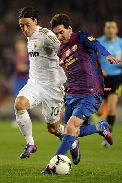 Özil y Messi pugnan por el balón.