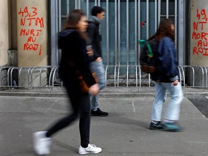 Tres jóvenes pasaban este 24 de marzo ante unas pintadas en París, con la leyenda "49.3", la norma legal que ha permitido aprobar por decreto la ley de las pensiones, y "Muerte al rey".