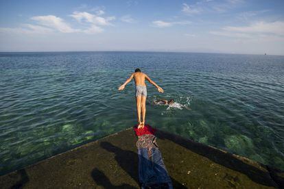 Un refugiado se lanza de cabeza al mar en el puerto de Mitilene, en la isla de Lesbos (Grecia).