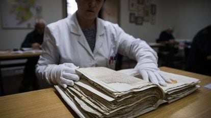 Una trabajadora del Archivo Histórico Diocesano de Santiago consulta datos en un manuscrito.
