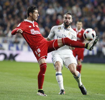 El defensa del Real Madrid, Dani Carvajal (d) lucha por el balón con el defensa Sergio Escudero (i) del Sevilla durante el partido de ida de los octavos de la Copa del Rey.