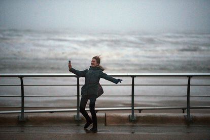 Rachas de más de 100 kilómetros por hora azotan a varias zonas de Reino Unido. Una mujer trata de hacerse una foto con el móvil en el paseo marítimo de Blackpool, una de las localidades afectadas por el temporal.
