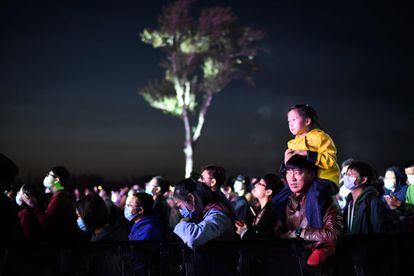 Un hombre sostiene a una niña durante un concierto celebrado bajo el cielo de Pekín el pasado lunes.