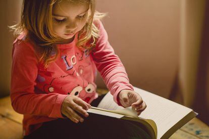 Una niña consulta un libro.