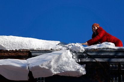 Una mujer limpia la nieve del tejado de su casa en Brooklyn, Nueva York.