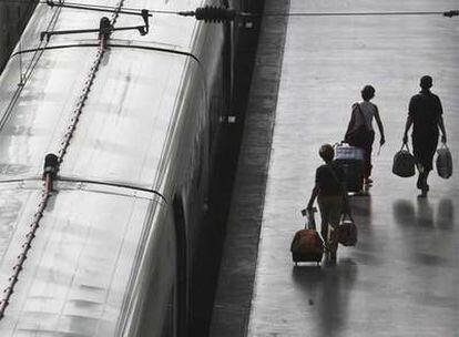 Tres pasajeros afectados por los retrasos caminan por uno de los andenes de la estación de Atocha de Madrid.