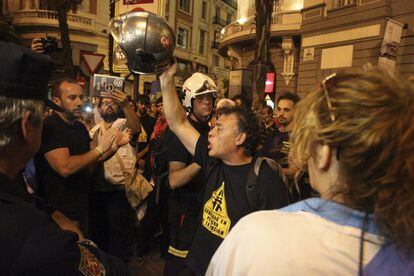 Un bombero gesticula con su casco alzado en la mano durante las protestas contra los recortes de anoche.