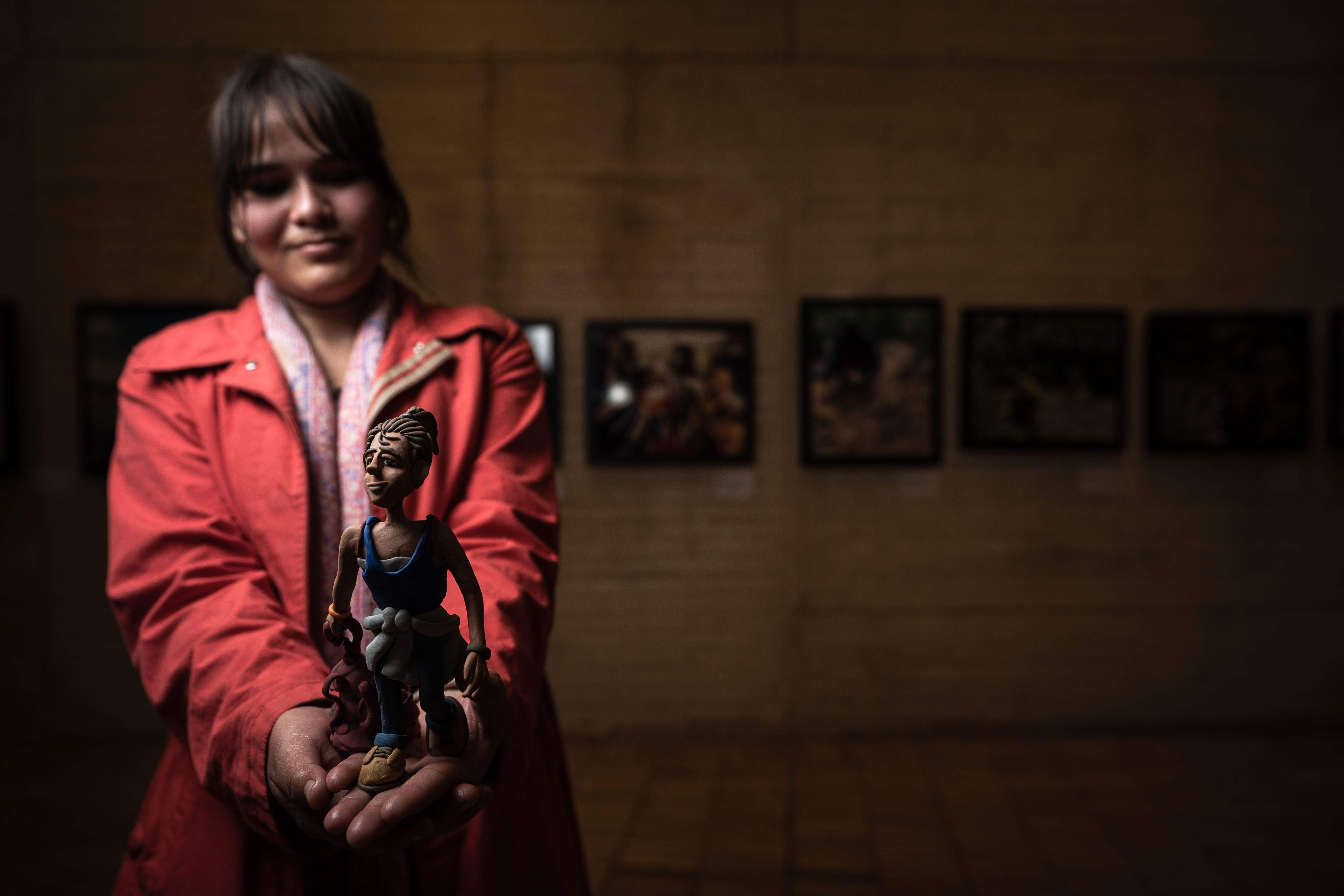 Gabriela Liebano, migrante venezolana, sostiene una figura de plastilina de ella misma hecha por Edgar Álvarez.