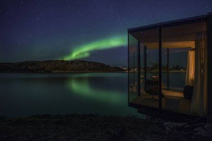 Una aurora boreal es visible desde una de las cabañas que integran el complejo turístico de la isla de Manshausen (Noruega).