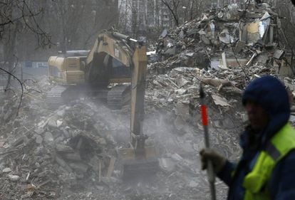 Una excavadora trabaja retirando parte de los escombros de un edificio demolido, en Moscú.