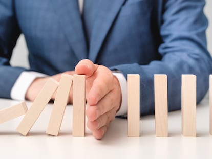 Business risk, crisis effect. Businessman protect falling domino with hand