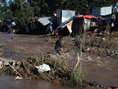 Un hombre cruza un río en un asentamiento informal durante las inundaciones en Durban, Sudáfrica.