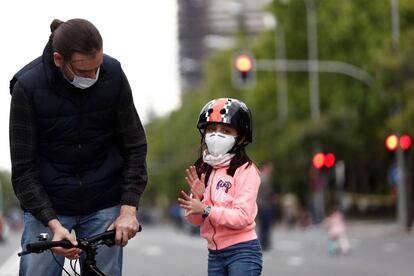 Un hombre pasea con su hija por el Paseo de la Castellana.