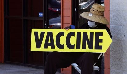 Un hombre sostiene un cartel indicador de un centro de vacunación, en Los Ángeles (California).