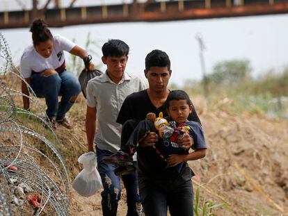 Inmigrantes caminan al lado de un alambre de púas en Eagle Pass, en la frontera entre Texas y México