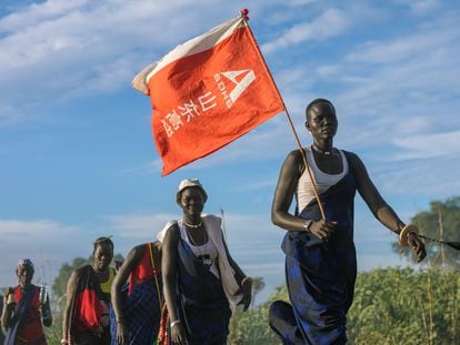 Una mujer de la tribu mundari pasea con una bandera con letras chinas que halló las obras de una carretera en Terekeka (Sudán del Sur) en 2019.