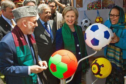 El presidente afgano, Hamid Karzai, y la jefa de la diplomacia estadounidense, Hillary Clinton, visitan ayer un bazar en Kabul.