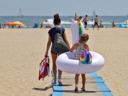 Una niña carga con su flotador hacia la orilla de la playa de Las Arenas de Valéncia. 