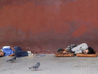 Dos personas duermen en una acera en Buenos Aires. 