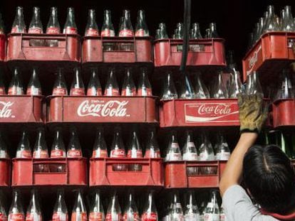 Un trabajador apila cajas vacías de botellas de Coca-Cola en México.