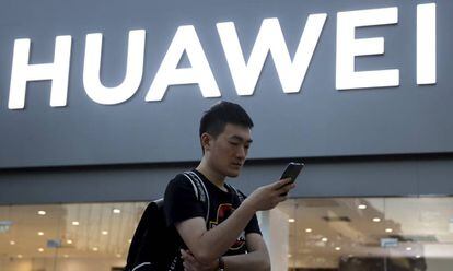 Un hombre usando su smartphone delante de una tienda de Huawei en Beijing.