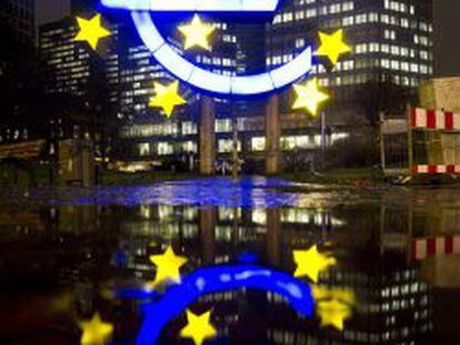 La escultura del Euro se ve iluminada en frente de una sede del Banco Central Europeo (ECB)