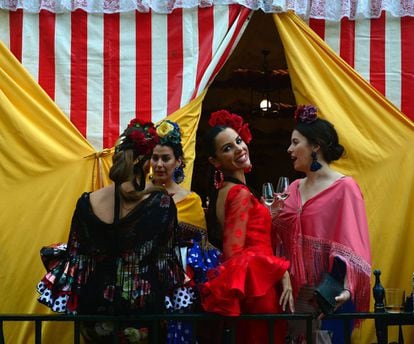 A woman wearing a traditional Sevillian dress smiles as she drinks "Fino" wine with friends during the "Feria de Abril" (April Fair) in Sevilla on April 30, 2017. 
The fair dates back to 1847 when it was originally organized as a livestock fair but has turned into a week of flamenco dancing, music and bullfighting.  / AFP PHOTO / CRISTINA QUICLER