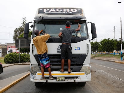 Migrantes venezolanos limpian parabrisas de autos en las calles de Lima (Perú), en marzo de 2020.