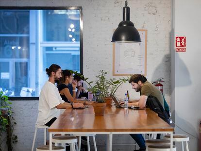 Jóvenes trabajan en la cafetería del espacio de 'coworking' Itnig del barrio del Poblenou de Barcelona.