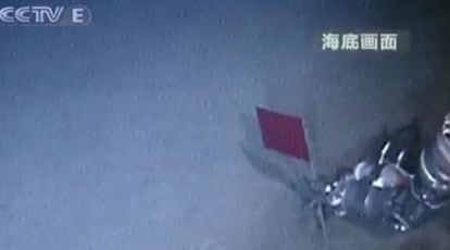 Un brazo robótico del submarino <i>Jialong</i> planta una pequeña bandera china en el fondo del Mar de China.