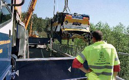 El autobús siniestrado en Boborás (Ourense) y en el que murieron cinco personas, es elevado al puente desde el que cayó.