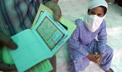 Una mujer observa el pasaporte y otros documentos oficiales en manos de un pariente en la ciudad de Nueva Delhi, en 2003.