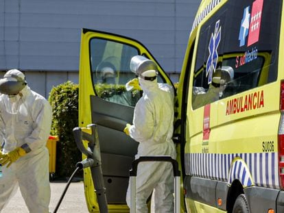 Dos bomberos de la Comunidad de Madrid limpian una ambulancia del SAMUR utilizada para trasladar enfermos de coronavirus en el punto de desinfección cercano al hospital de campaña montado en el recinto madrileño de IFEMA, en Madrid, el 3 de abril de 2020.