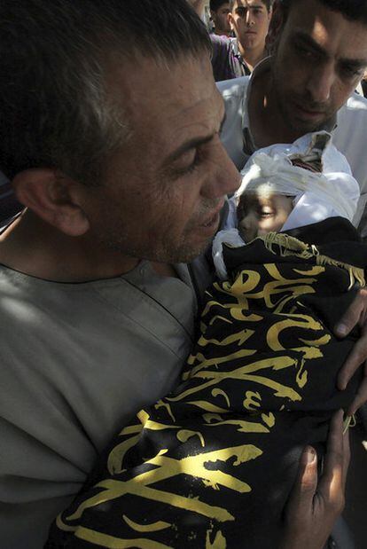 Un hombre lleva el cadáver de su nieto, víctima de un ataque aéreo israelí, durante el funeral celebrado ayer en Gaza.