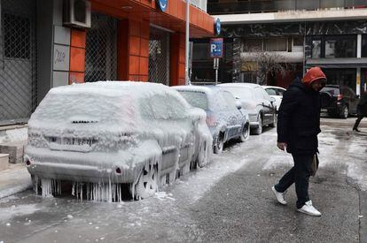 Un hombre pasa cerca de varios coches congelados en Salónica (Grecia). 