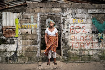 Confort Nyenetue poses at the old door of her house.  He slept for a year at school, where he left every morning with the first rays of sun.