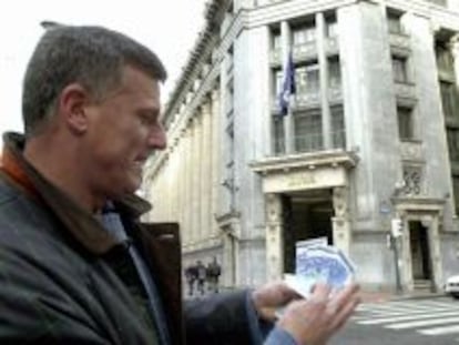 Un hombre muestra unos billetes de euro retirados de un cajero autom&aacute;tico.