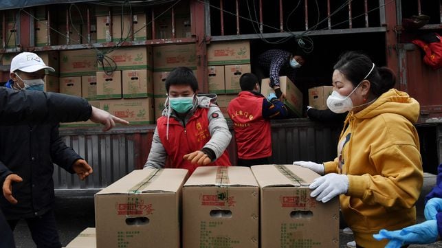 Un grupo de voluntarios descarga alimentos para un complejo de viviendas en Wuhan, el foco de la epidemia de coronavirus.