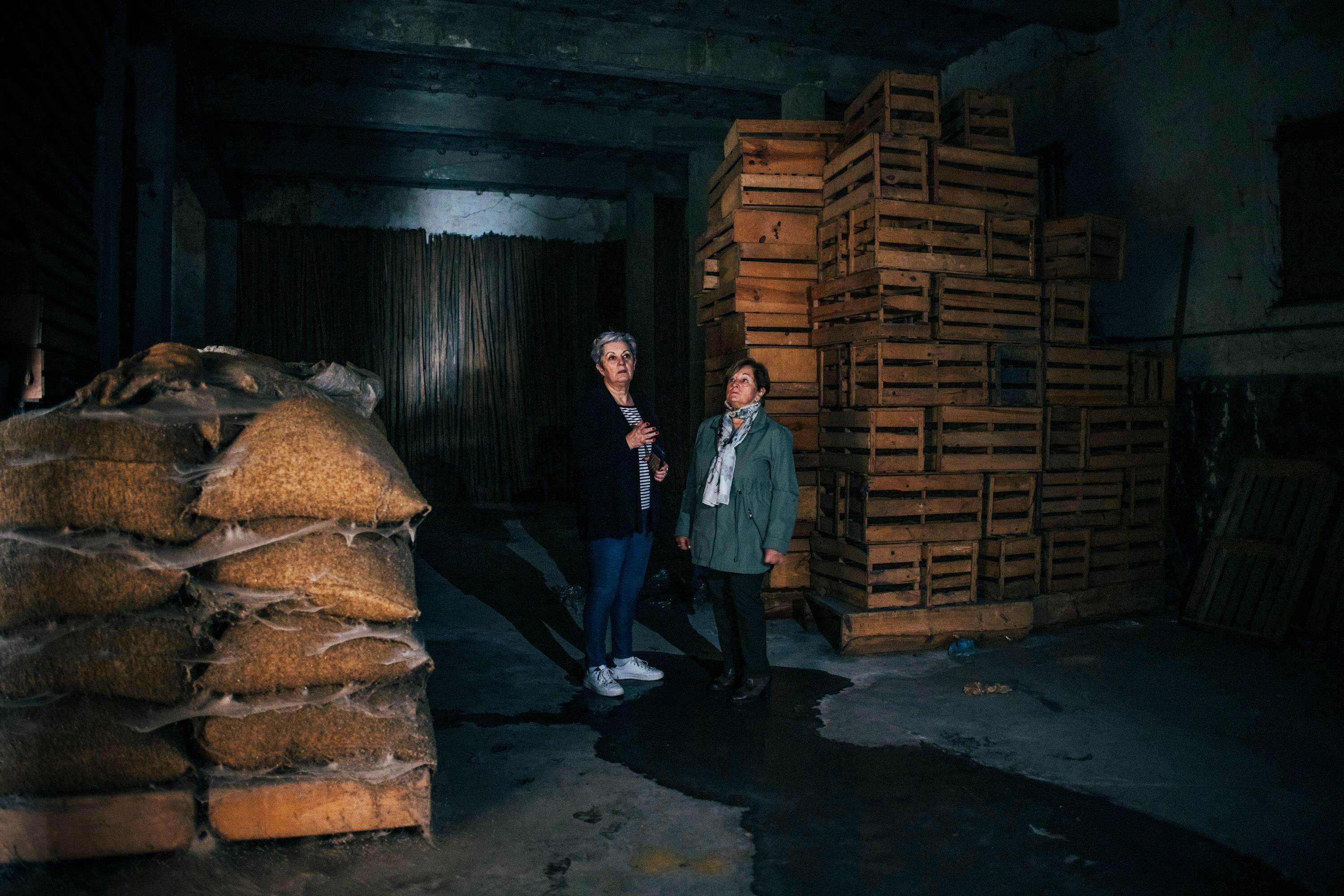 Fifa Vázquez y Mari Carmen González, en el almacén de Nicanor y Eulogio González Valeiras, entre viejas cajas para huevos, palos para colgar jamones y sacos de cornezuelo.