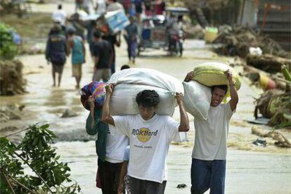 Varios afectados por las inundaciones evacuan sus casas con sus pertenencias, ayer  a 70 kilómetros de Manila.