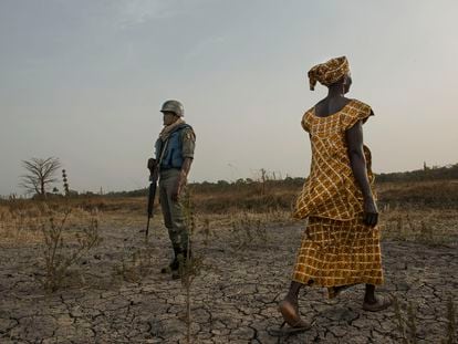 Una agricultora pasa por delante de un militar en unos arrozales en Ziguinchor (Senegal).