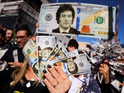 Simpatizantes de Javier Milei agitan reproducciones de dólares con su cara en en Buenos Aires.