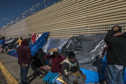 Un grupo de migrantes aguarda en un campamento improvisado frente al muro fronterizo en San Luis Río Colorado, en Sonora.